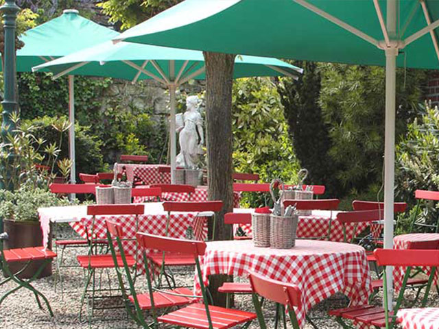 Biergarten der Gaststätte Vennen mit grünen Sonnenschirmen und rot-weiß gedeckten Tischen